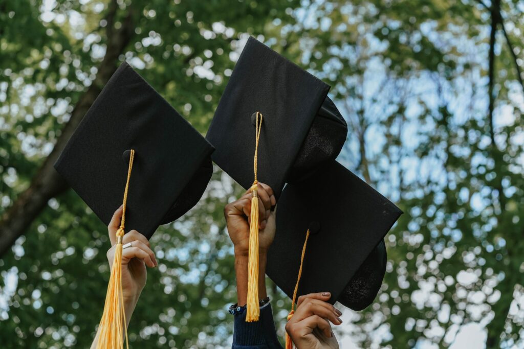 Add Your School image of hands holding graduation caps in the air