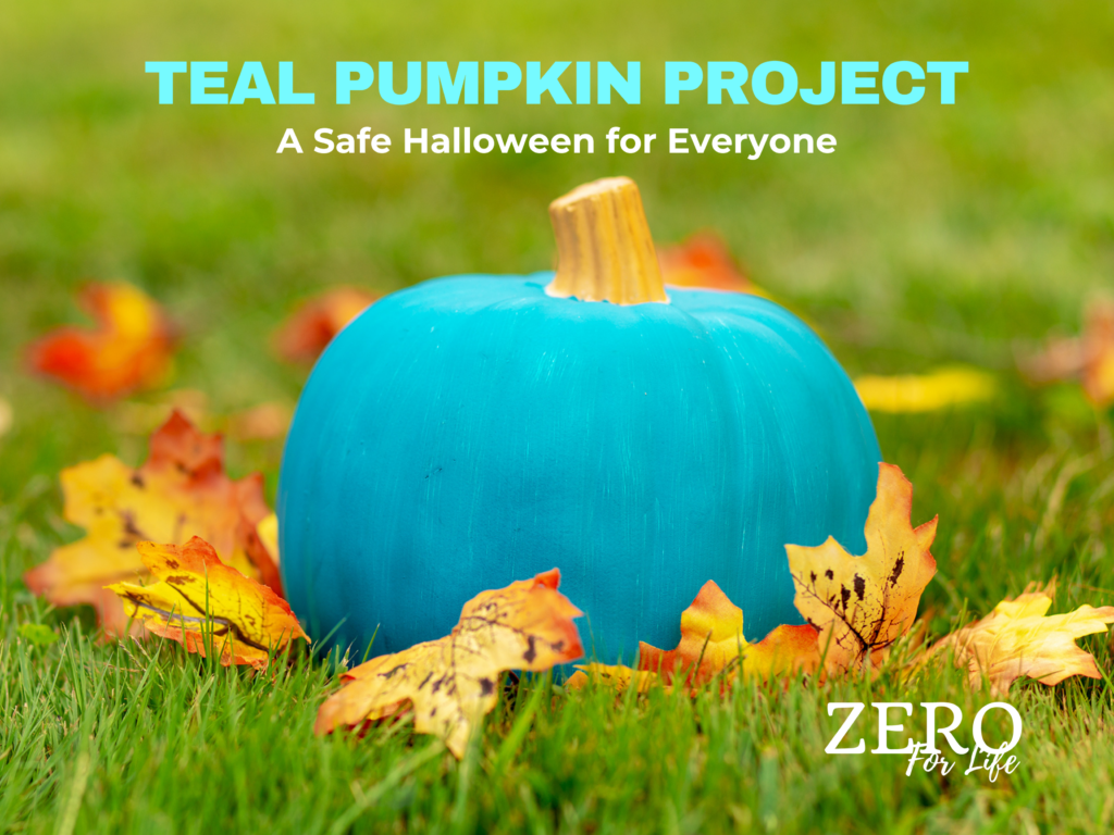 Teal Pumpkin Project. A Safe Halloween for Everyone. Image of teal colored painted pumpkin on a lawn surrounded by fall leaves.